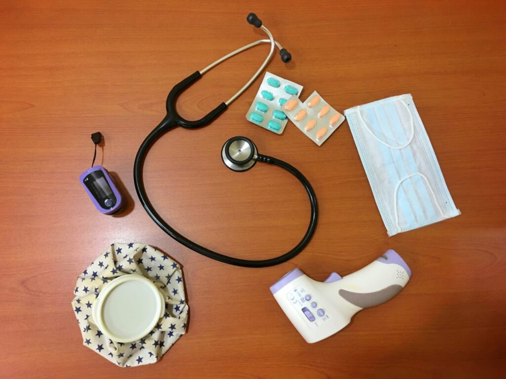 Materiais médicos usados pelo médico da família, como estetoscópio, comprimidos e máscara sobre uma mesa.
